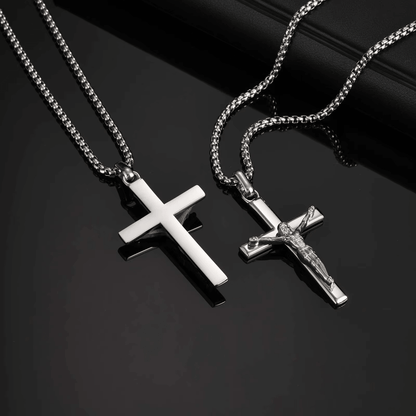 Two silver cross necklaces on a dark surface