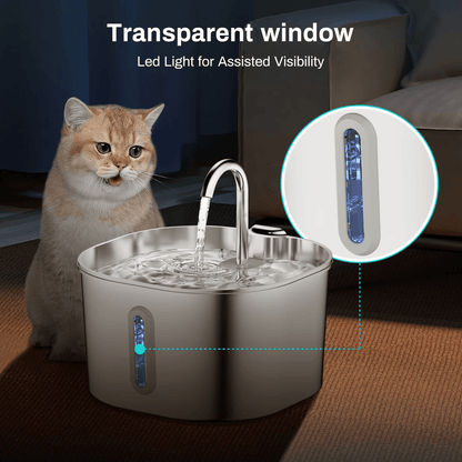 Cat sitting next to a pet water fountain with a transparent window and LED light feature.